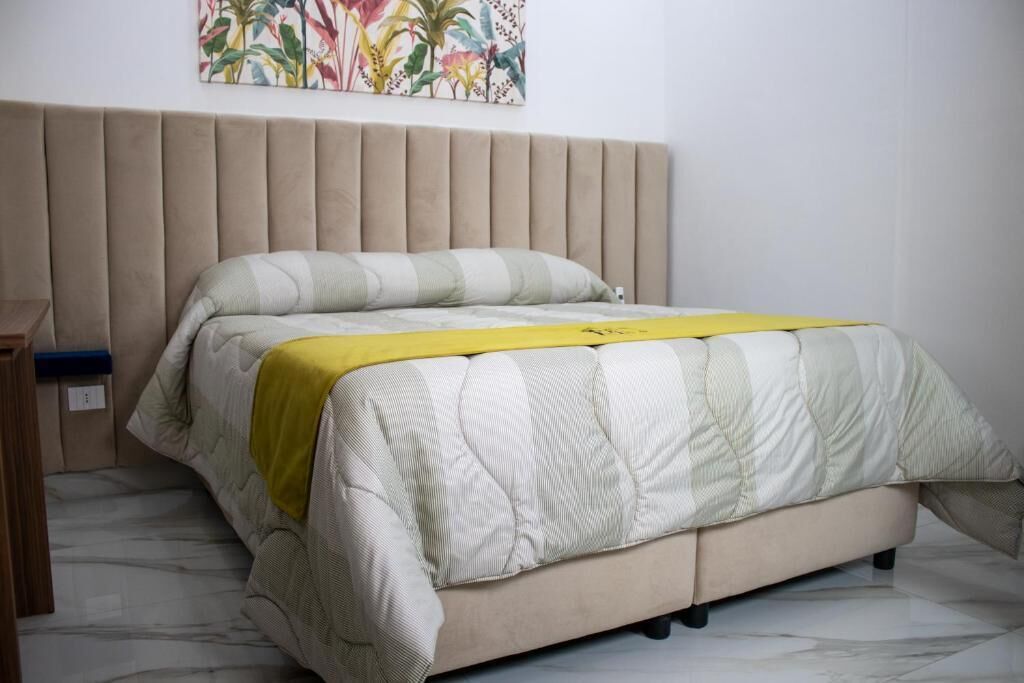 A bed with a beige headboard, a quilted bedspread, and a yellow blanket.