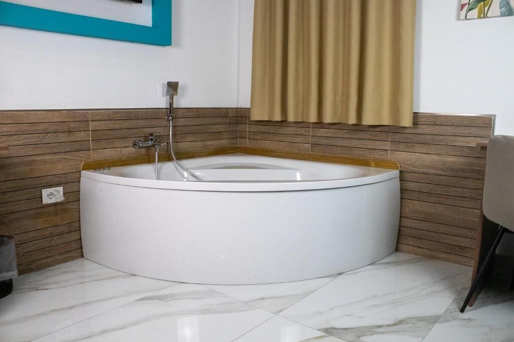A modern bathroom with a freestanding bathtub, wooden paneling, and a tiled floor.