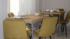 A dining area with a wooden table, yellow chairs, and a glass vase on the table. - Augustea Travel (San Marcellino)