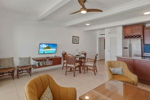 A living room with a TV, seating, a dining table, and a kitchen area. - Oceanfront Condo | Ocean View & Pool 210 (Puerto Plata)