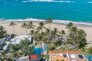 A beachside resort with a swimming pool, palm trees, and ocean views. - Oceanfront Condo | Ocean View & Pool 210 (Puerto Plata)