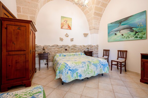 A bedroom with a bed, a wooden wardrobe, a nightstand, a chair, and a painting on the wall. - Villa Tonia - Stanza Edera Apartment with Private Terrace, Wi-Fi, and Air Conditioning (Fasano)