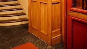 A wooden staircase with a red door and a glass window with a geometric pattern. - HOTEL LA LOUISIANE (Paris)