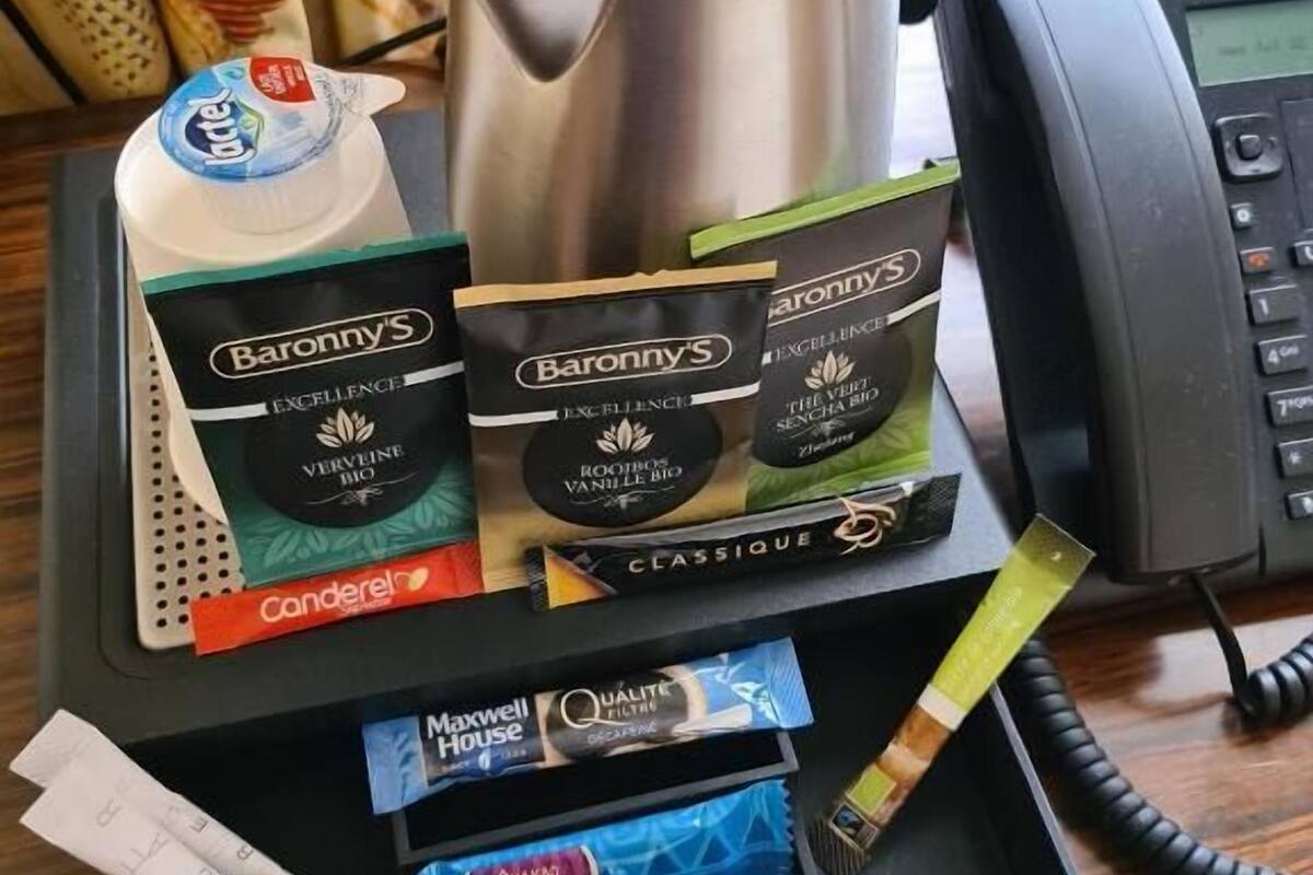 A tray with coffee maker, milk, tea bags, and a phone.