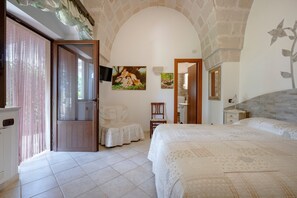 A bedroom with a large bed, a chair, a small table, and a painting on the wall. - Apartment 'Villa Tonia - Stanza Gelsomino' with Private Terrace, Wi-Fi and Air Conditioning (Fasano)