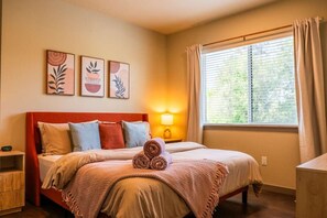 Une chambre à coucher avec un lit, une table de chevet, une lampe et une fenêtre avec des rideaux.
