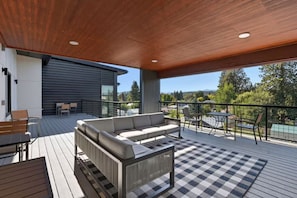 Une terrasse extérieure moderne avec un tapis à carreaux, un canapé et une table.