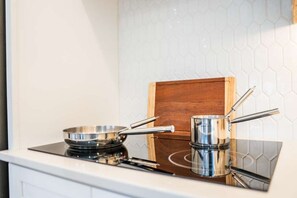 Eine Küche mit einem modernen Induktionskochfeld, Edelstahlkochgeschirr und einem Schneidebrett aus Holz.