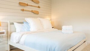 Ein Bett mit weißer Bettwäsche, ein Nachttisch und ein an der Wand befestigtes Holzschild.
