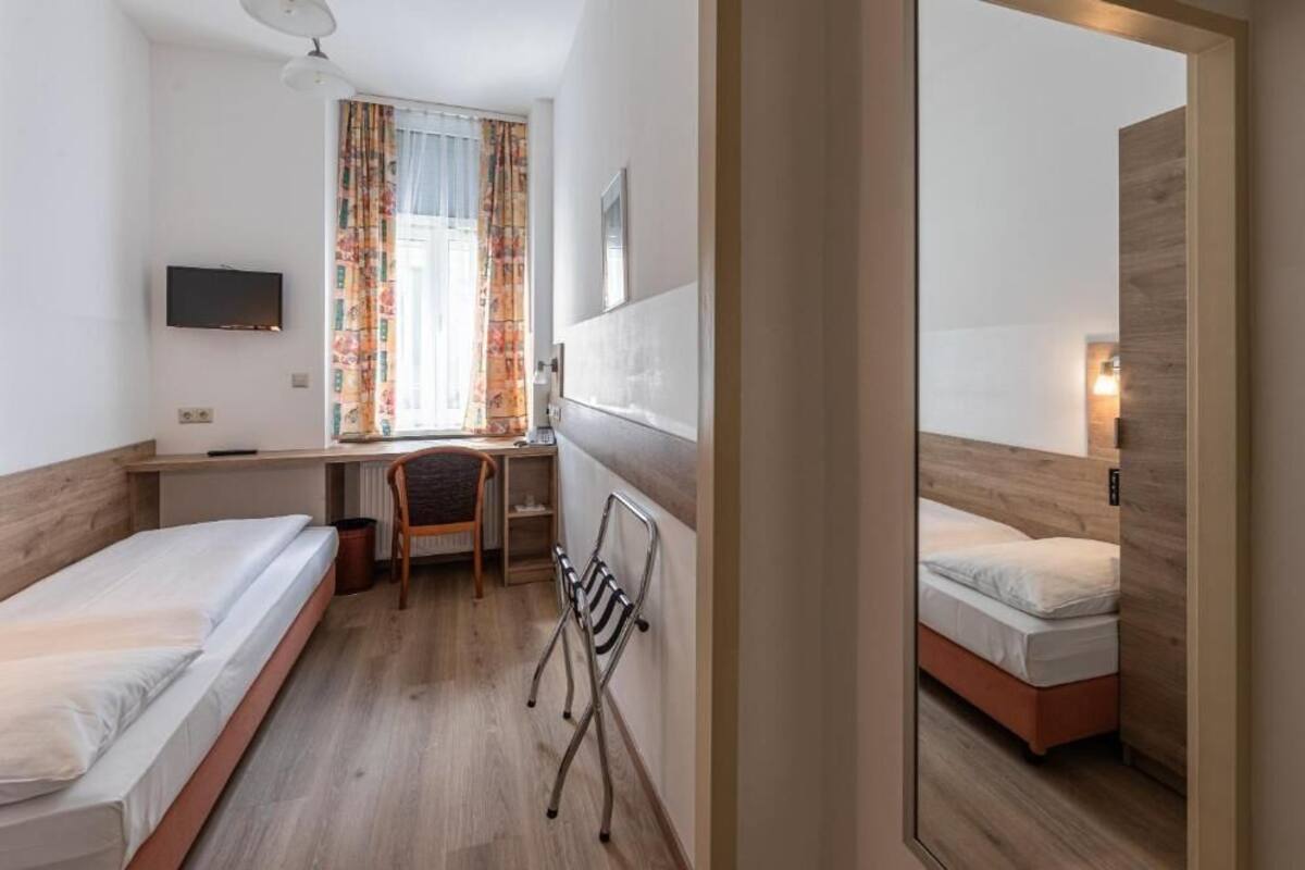 Una habitación de hotel con cama, escritorio, silla y televisor.