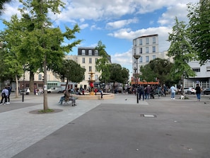 Ein öffentlicher Platz mit Bänken, einem Brunnen und umgebenden Gebäuden.