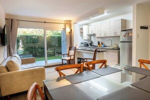 A modern kitchen with a dining area, large windows, and a sliding glass door to the outdoors. - Hermoso Departamento 3D a pasos de Centro de Pucón (Pucon)