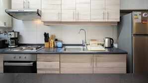 Une cuisine moderne avec des meubles en bois clair, des appareils en acier inoxydable et un plan de travail noir.