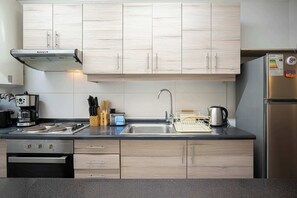 A modern kitchen with light wood cabinets, stainless steel appliances, and a black countertop. - Hermoso Departamento 3D a pasos de Centro de Pucón (Pucon)