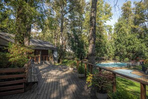 A wooden deck with a pool, surrounded by trees and greenery. - Hermoso Departamento 3D a pasos de Centro de Pucón (Pucon)
