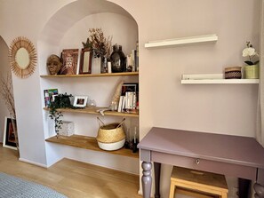 Ein Zimmer mit einem Holztisch, einem Bücherregal und einem Spiegel.
