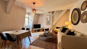 A loft-style living space with a dining area, a sofa, a TV, and a staircase. - Quiet 2-bdrm flat in central Strasbourg (Strasbourg)