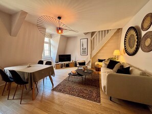 Ein Loft-Wohnraum mit Essbereich, einer Couch, einem Fernseher und einer Treppe.
