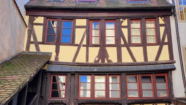 A traditional half-timbered building with a staircase, two visible windows, and a door with a small garden area in front. - Quiet 2-bdrm flat in central Strasbourg (Strasbourg)