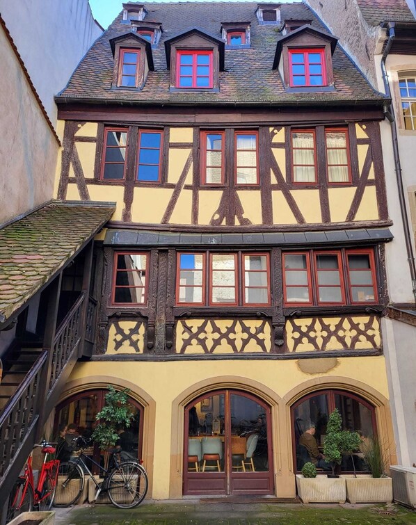 Ein traditionelles Fachwerkhäuschen mit Treppe, zwei Fenstern und einer Tür, vor der sich ein kleiner Garten befindet.