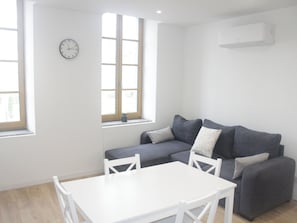 A modern living room with a white table and chairs, a grey sofa, and a window with a view. - Apartment with view on city of Carcassonne (Carcassonne)