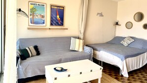 Et værelse med to senge, en sofa, et lille bord og spejle på væggen.