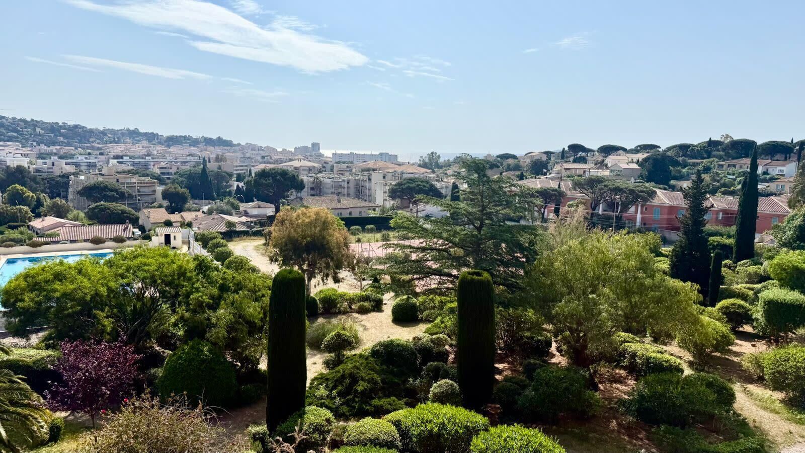 A garden with neatly trimmed bushes and a clear view of a residential area in the background.