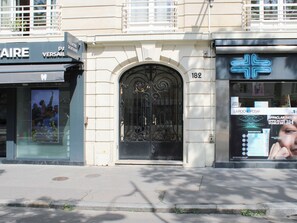 A building facade with a large arched entrance, a sign for 'LA ROCHE POSAY,' and a visible address number '182.' - Bright balcony near Roland-Garros (Paris)