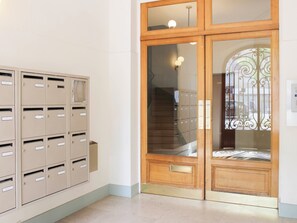 A hallway with beige mailboxes and a wooden double door with glass panels. - Bright balcony near Roland-Garros (Paris)