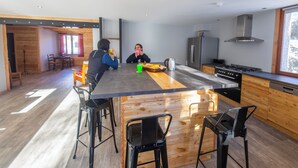 A modern kitchen with a central island, bar stools, and a dining area with chairs.