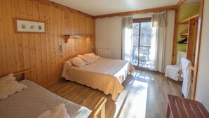 A room with wooden walls, a bed, a chair, and a window with curtains.