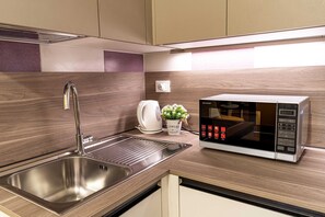 A modern kitchen with a stainless steel sink, a microwave, and a small potted plant. - Daisy Flowers by Wonderful Italy (Venice)