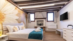 Un dormitorio con cama, chimenea, televisión y techo de madera.