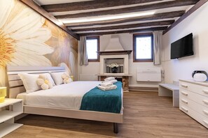 A bedroom with a bed, a fireplace, a TV, and a wooden ceiling. - Daisy Flowers by Wonderful Italy (Venice)