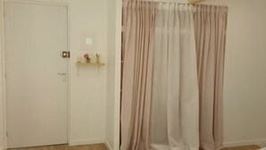 A room with a closed door, a shelf with items, and a curtain.