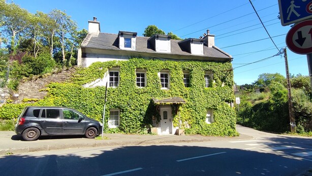 A building with ivy-covered walls, a car parked in front, and a pedestrian crossing sign.
