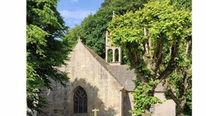 A stone church with a pointed roof and a large arched window.