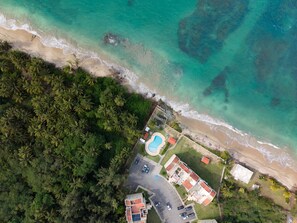 Eine Luftaufnahme eines Anwesens an der Küste mit Schwimmbad, mehreren Gebäuden und einem Strand.