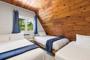 A bedroom with three beds, wooden ceiling, and a window with curtains.