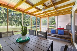 Une terrasse couverte avec une table, des chaises, un canapé et une vue sur un lac.