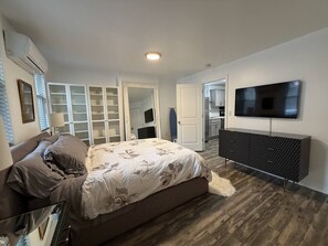Ein Schlafzimmer mit Bett, Fernseher, Kleiderschrank und Spiegel.