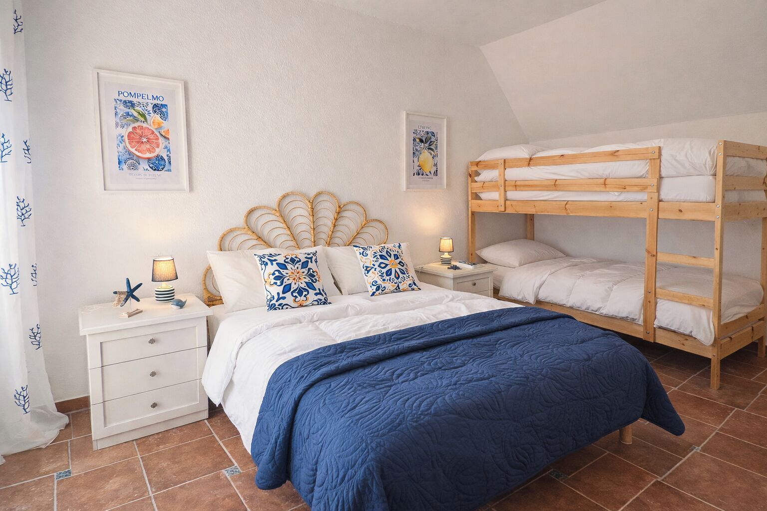 A bedroom with a bunk bed, a single bed, a nightstand with a lamp, decorative pillows, and wall art.