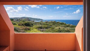 A balcony with a view of a coastal landscape, including greenery and the sea. - Casa Audrey by Wonderful Italy (Santa Teresa di Gallura)