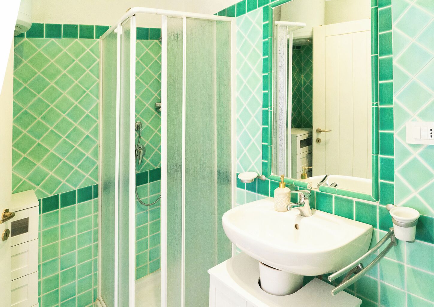 Een badkamer met douche, wastafel en spiegel.