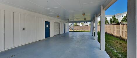 A covered outdoor area with a concrete floor, white walls, and a blue door.