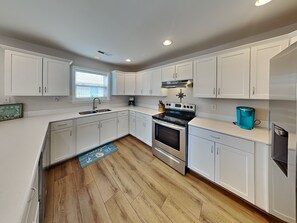 A modern kitchen with white cabinets, a stainless steel oven, and a coffee maker.