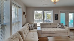 Una sala de estar con un sofá modular, una mesa de centro y un ventanal corredero que da a un balcón.