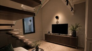 Een moderne woonkamer met een bank, een salontafel, een flatscreen televisie en een potplant.