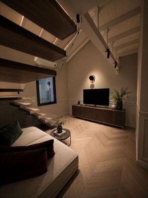 A modern living room with a sofa, a coffee table, a flat-screen TV, and a potted plant. - THE PENTHOUSE by ASTRA COLLECTION (Bologna)