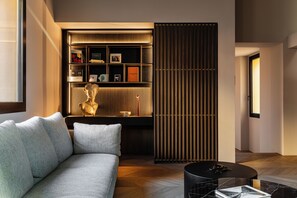 A modern living room with a sofa, a coffee table, a decorative sculpture, and a built-in shelving unit with various items. - ASTRA PENTHOUSE (Bologna)